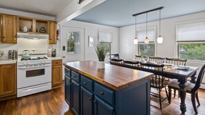 A kitchen with wooden cabinets, a white stove, and a dining area with a wooden table and chairs.