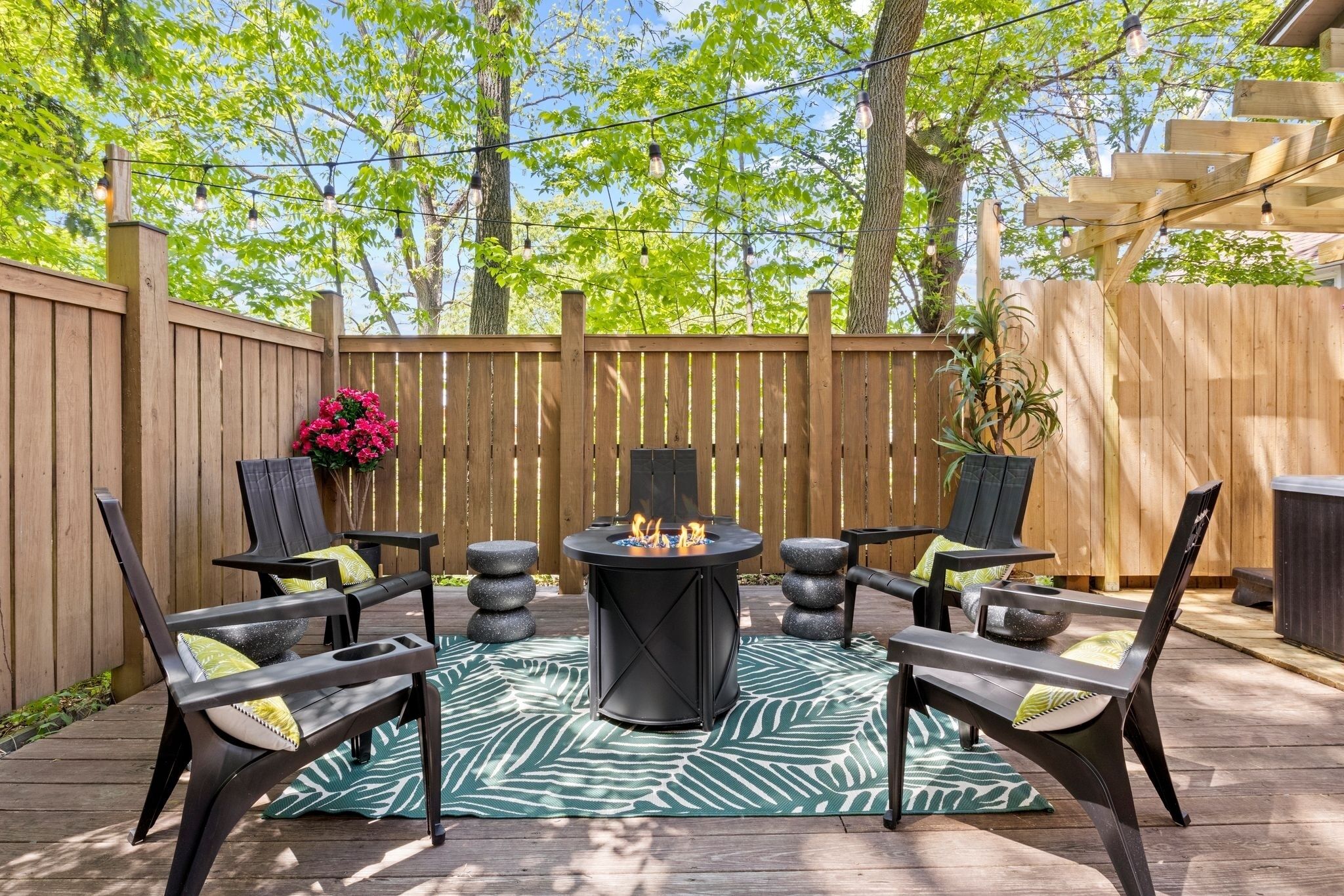 Eine Terrasse im Freien mit einem runden Tisch, vier Stühlen und einer Feuerstelle.
