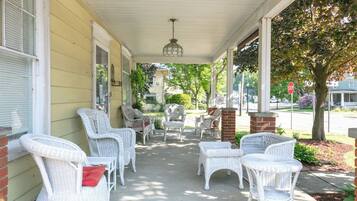 A covered porch with wicker furniture and a stop sign in the background.