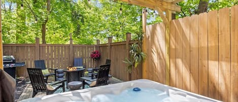 Un área de hidromasaje al aire libre con un pérgola de madera, asientos y una valla de madera.