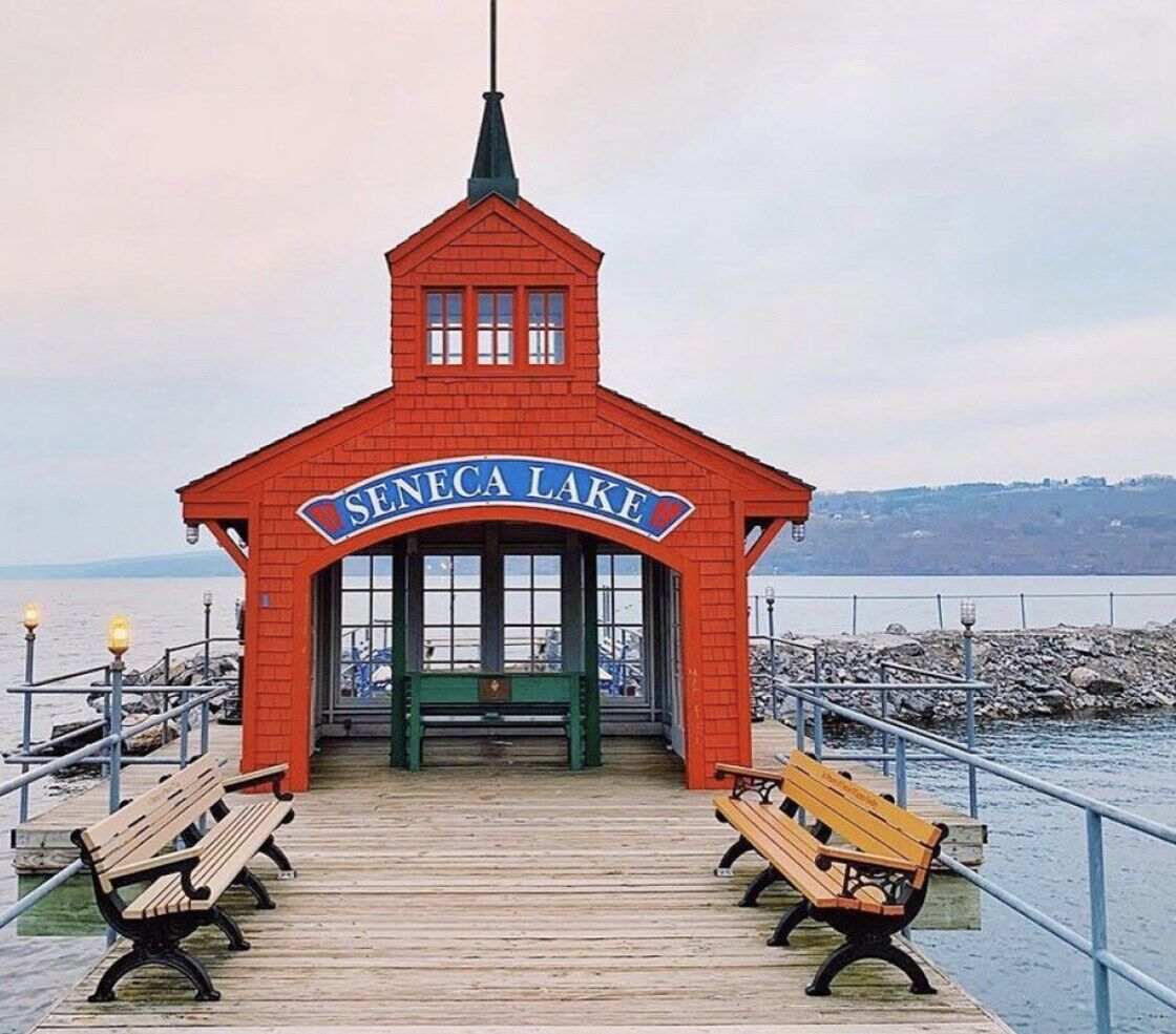 Un bâtiment en briques rouges, surmonté d’un toit vert, et portant une enseigne indiquant « Seneca Lake ».