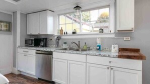 A kitchen with white cabinets, a granite countertop, a built-in microwave, and a window above the sink.