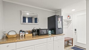 Une cuisine de taille réduite avec des meubles blancs, un four à micro-ondes, un grille-pain et un réfrigérateur.