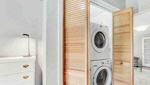 A laundry room with a washing machine and dryer, a white dresser with gold handles, and a wooden sliding door. - River Front! in the heart of Ithaca! (Ithaca)