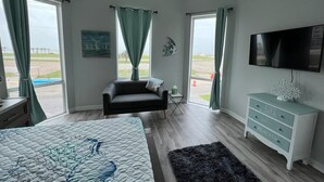 A bedroom with a bed, a sofa, a TV, and a dresser. - Beachy Escape for 2 Fun in The Sun Endless Charm! (Galveston)