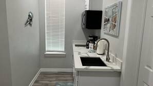 A compact kitchen with a sink, a coffee maker, and a microwave. - Beachy Escape for 2 Fun in The Sun Endless Charm! (Galveston)
