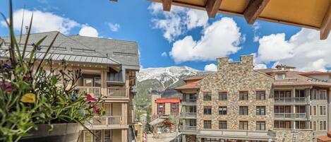 Un hotel con varios pisos, balcones y vistas a montañas nevadas.
