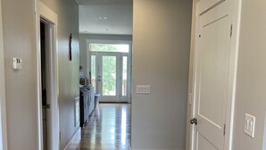 A hallway with wooden flooring, white walls, and a door on the right.