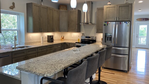 A modern kitchen with granite countertops, stainless steel appliances, and a central island with bar stools.