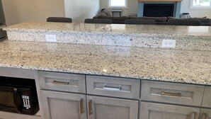A kitchen with granite countertops, built-in appliances, and a fireplace.