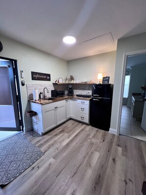 A modern kitchen with white cabinets, a wooden countertop, a built-in microwave, and a black refrigerator. - Spa Bath Suite w/ Private Patio (Port St Lucie)