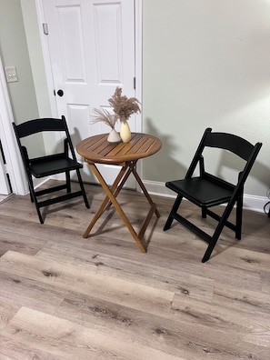A room with two black chairs, a round wooden table, and a white door.