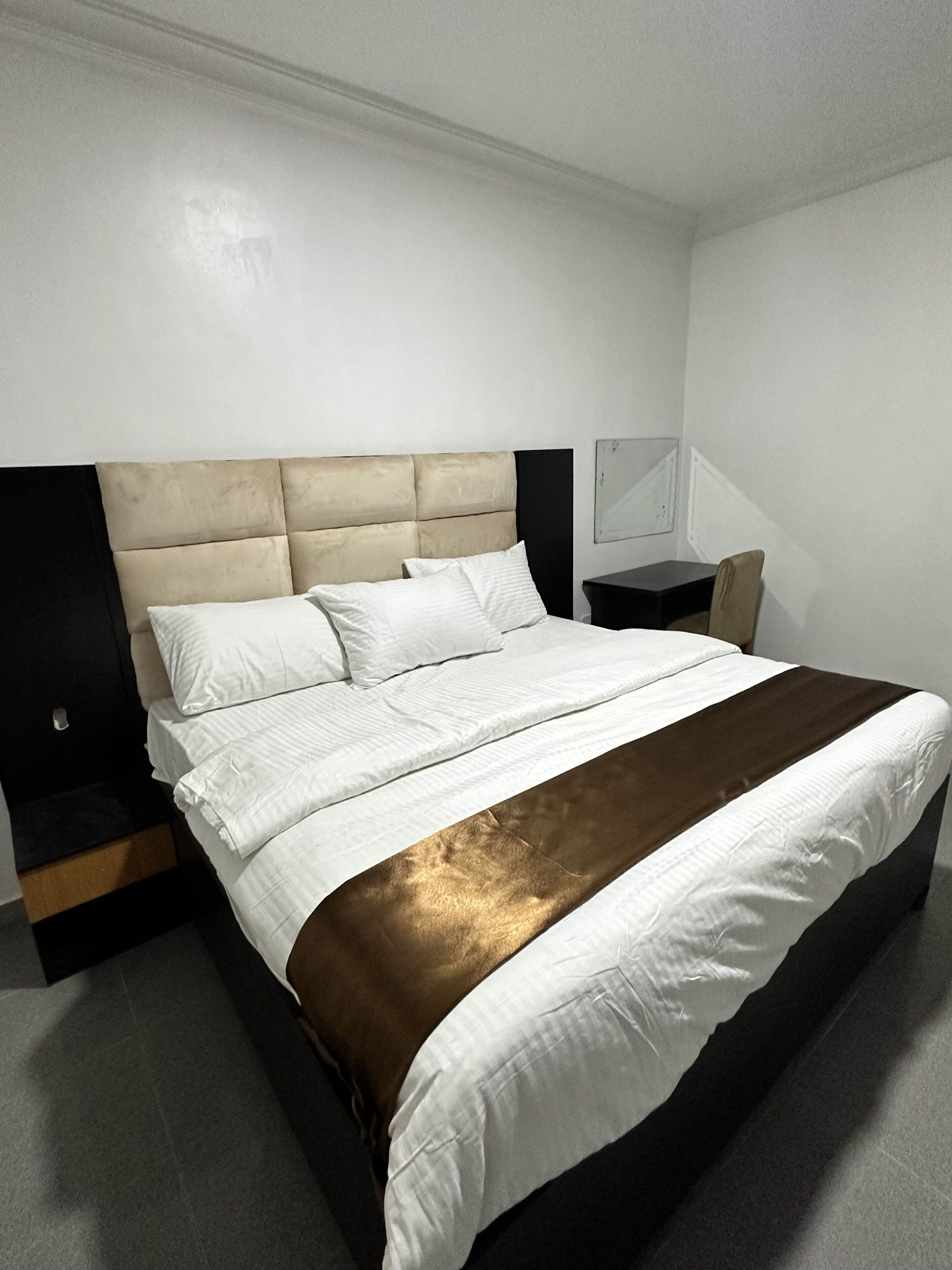 Ein modernes Hotelzimmer mit einem großen Bett, einem Nachttisch und einem kleinen Tisch.