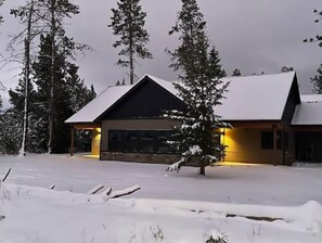 Set amidst a forest of tall evergreen trees, this lodge offers a garage door and covered outdoor space.