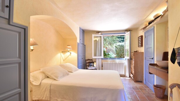 Une chambre à coucher avec un lit, une fenêtre, une chaise, une commode et un radiateur.