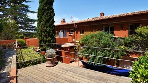 Une terrasse sur le toit, dotée d’une plateforme en bois, de plantes en pot et offrant une vue sur des bâtiments aux toits de tuiles.