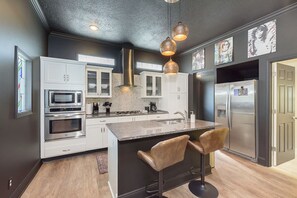 Cocina moderna con una isla central, electrodomésticos de acero inoxidable e iluminación colgante.
