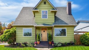 A two-story house with a green exterior, a front porch, and a number '204' on the door.