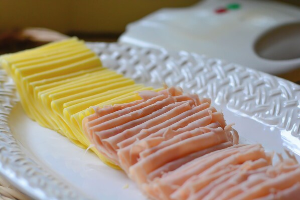 A white plate with neatly arranged slices of yellow and pink food items.