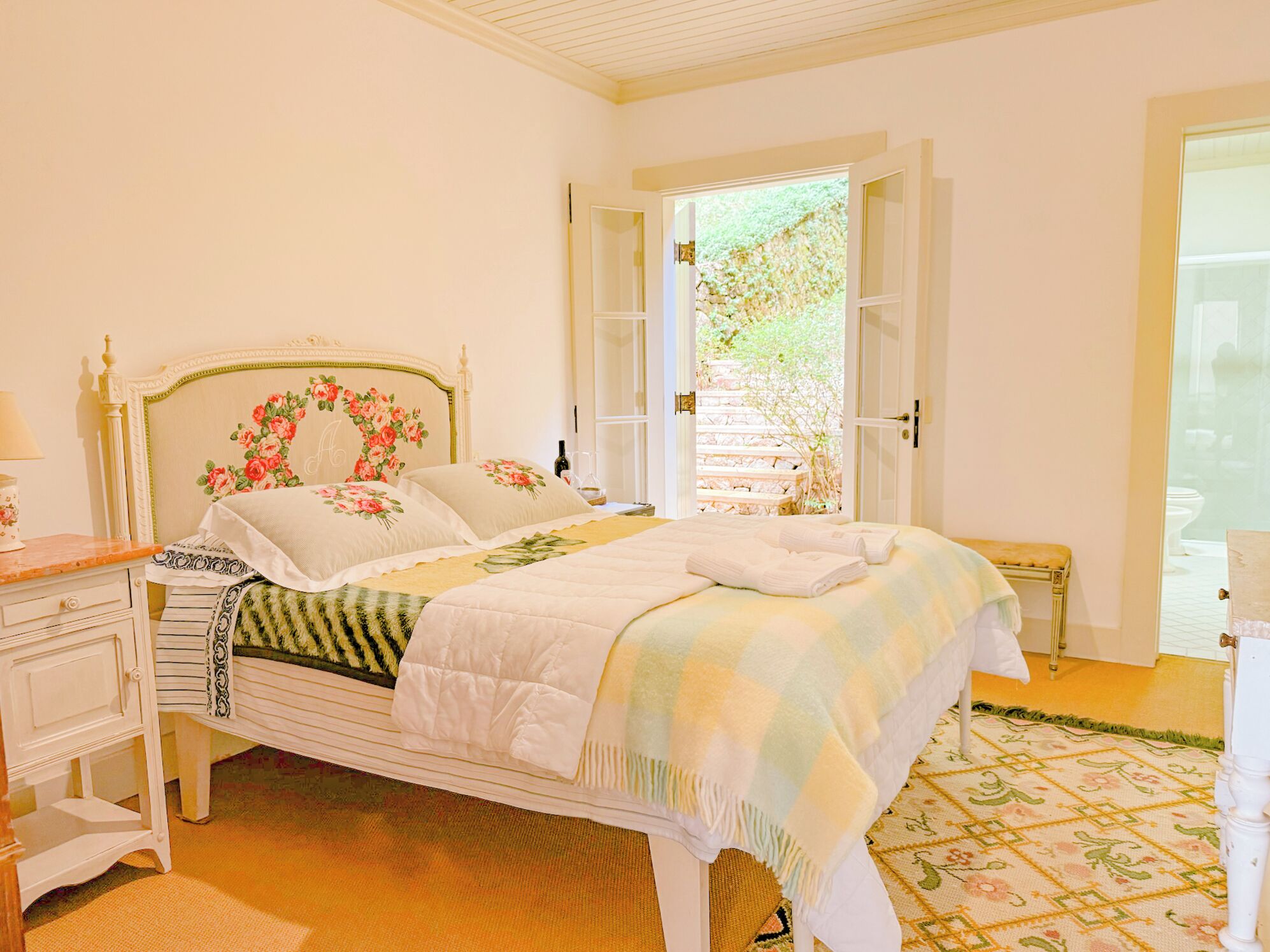 A bedroom with a bed, bedside tables, a dresser, and a window with an open door.
