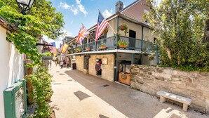 Une rue bordée d’immeubles, de drapeaux et d’un banc.