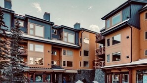 A multi-story building with a mix of wood and metal exterior, featuring balconies and large windows. - Feel at Home after a Day of Adventures in this Family friendly Retreat! (Canmore)
