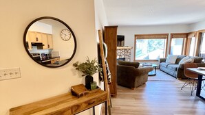 A modern living room with a wooden bench, a round mirror, and a stone fireplace. - Feel at Home after a Day of Adventures in this Family friendly Retreat! (Canmore)