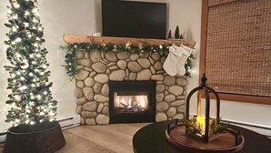 A cozy living room with a stone fireplace, a Christmas tree, and a television mounted on the wall. - Feel at Home after a Day of Adventures in this Family friendly Retreat! (Canmore)