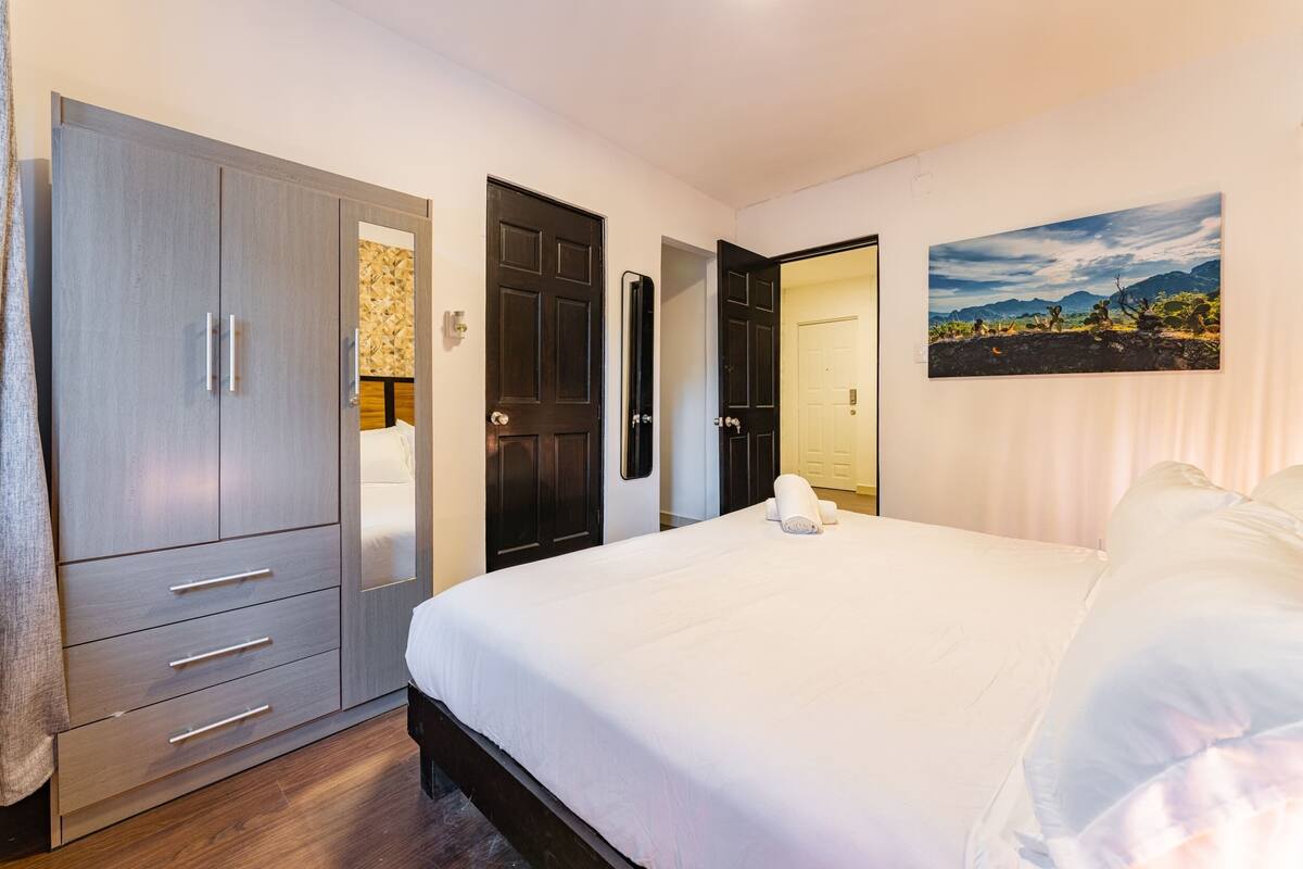 Une chambre à coucher avec un grand lit, une armoire et une porte donnant sur une autre pièce.