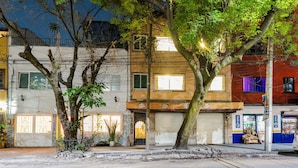 A building with a closed shutter, a visible entrance, and a tree in front. - Condesa Zamora Lofts by VH (Mexico City)