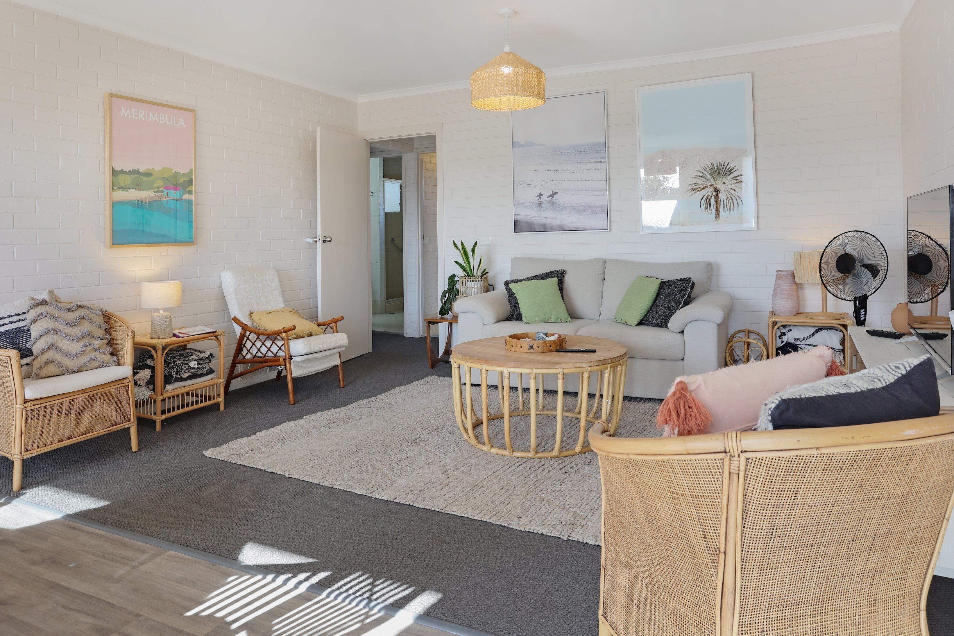 A modern living room with wicker furniture, a round coffee table, and artwork on the walls.