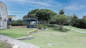 A residential backyard with a covered patio, a lawn, and a variety of plants. - Poolside - Ground floor opposite pool (Merimbula)