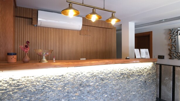 Un mostrador de recepción con encimera de madera, base de mosaicos y aire acondicionado instalado en la pared.