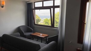Una habitación con sofá, una mesita y ventana con vistas a la vegetación y un paisaje lejano.