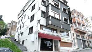 Un hotel de varios pisos con un llamativo letrero que dice 'Kryant Hotel', un toldo rojo y una escalera que conduce a la entrada.