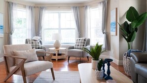 Una sala de estar acogedora con piso de madera, dos sillones, una mesa de centro y una mesita auxiliar.