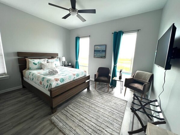 A bedroom with a bed, a ceiling fan, a TV, a desk, and a chair. - Charming Studio for 2 Endless Vibrant Location! (Galveston)