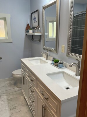 Ein Badezimmer mit zwei Waschbecken, einer Toilette und einer Duschkabine.