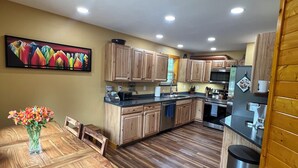 Una cocina moderna con armarios de madera, una mesa de comedor con sillas y un jarrón con flores.