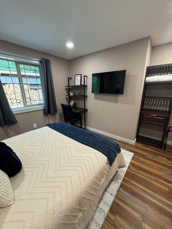 Ein Schlafzimmer mit Bett, Schreibtisch, Stuhl, Fernseher und Kleiderschrank.