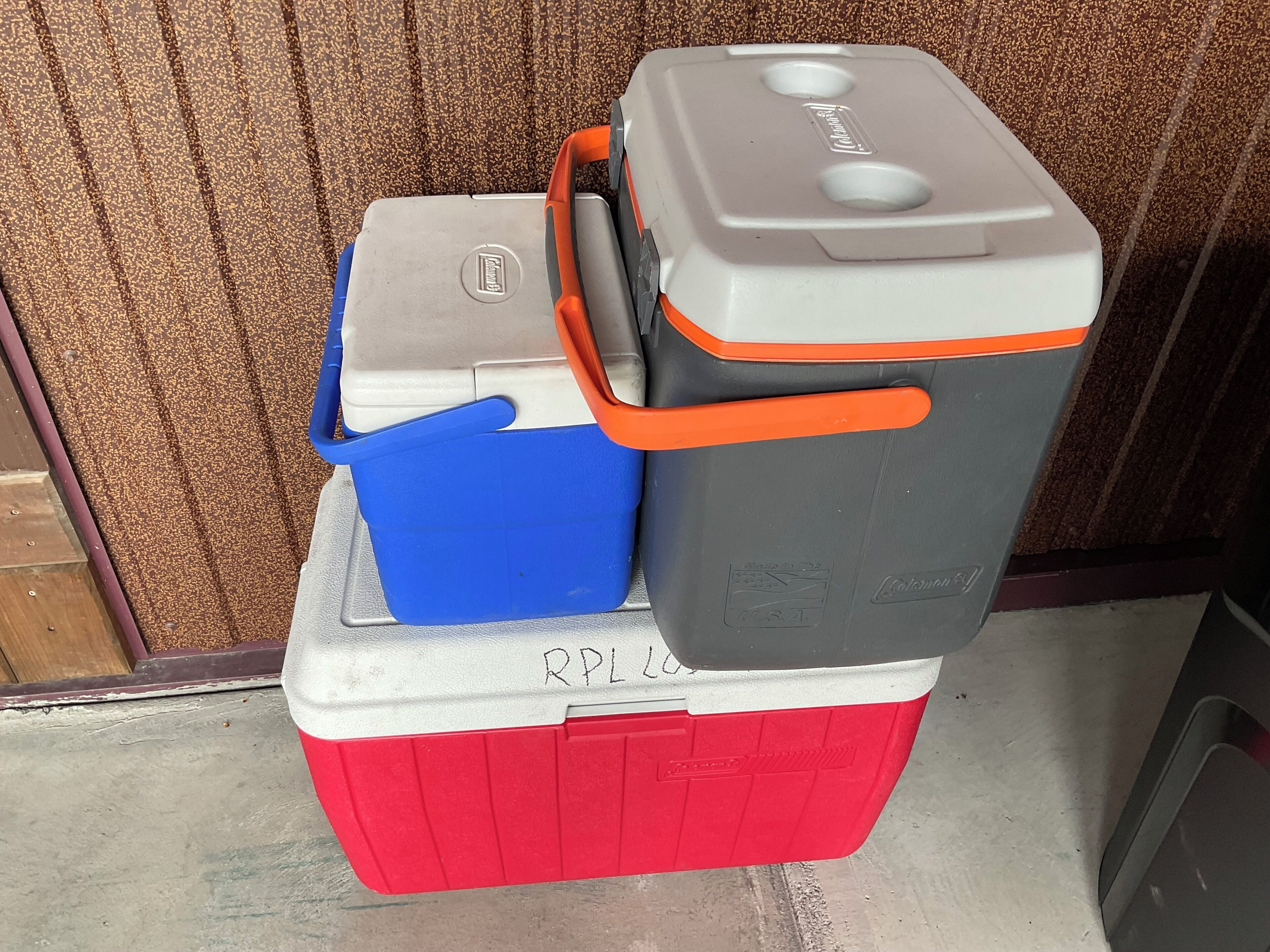 A red cooler with the label "RPL 20" and a blue container on top.