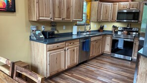 Una cocina con armarios de madera, un lavamanos de acero inoxidable, un microondas y un horno.