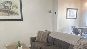 Een woonkamer met een grijze modulaire bank, een houten salontafel en een ingelijste foto aan de muur.