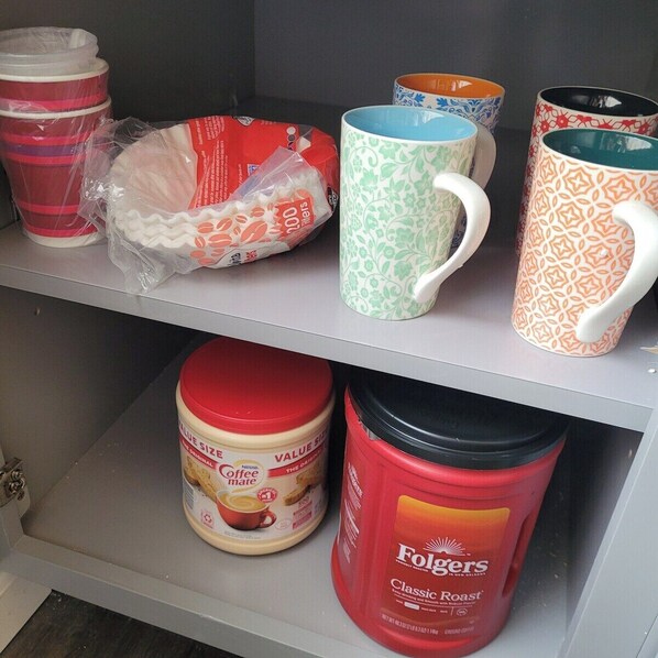 A shelf with various coffee mugs and containers.