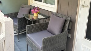 A small outdoor seating area with wicker chairs and a glass table, a window with blinds, and a door with a screen. - Beautiful & Stylish 2 BR & 2.5 Baths 10min downtown, 5min Lexington Med Center (Columbia)