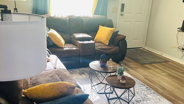 A living room with a brown sofa, yellow and blue cushions, a small round coffee table, and a lamp. - Beautiful & Stylish 2 BR & 2.5 Baths 10min downtown, 5min Lexington Med Center (Columbia)