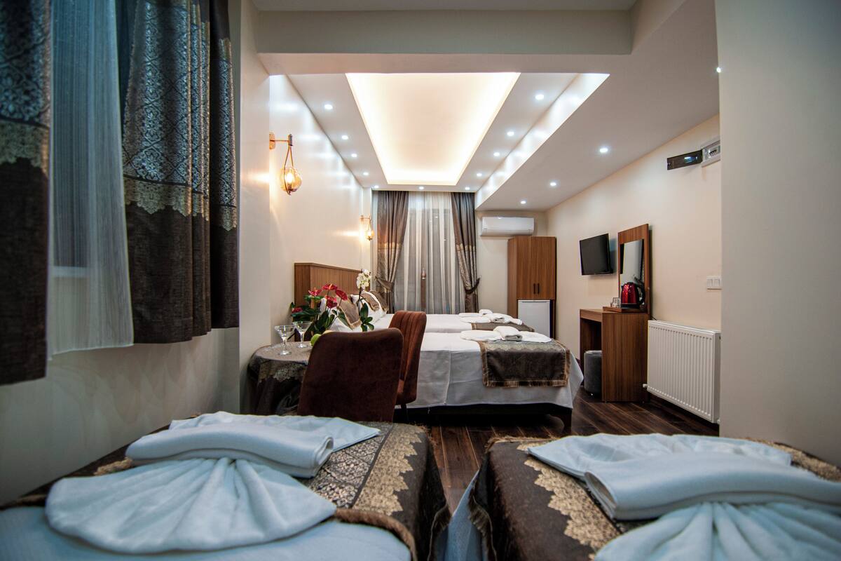 A hotel room with a bed, a desk, a chair, a TV, and a mirror.