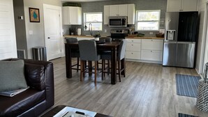 Eine moderne Küche mit weißen Schränken, einem Edelstahlkühlschrank und einem Essbereich mit einem Holztisch und Stühlen.