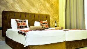 A double bed with a wooden headboard, two pillows, and a blanket. There is a bottle and glasses on the nightstand. - Te Bujtina Hotel&Restaurant (Golem)