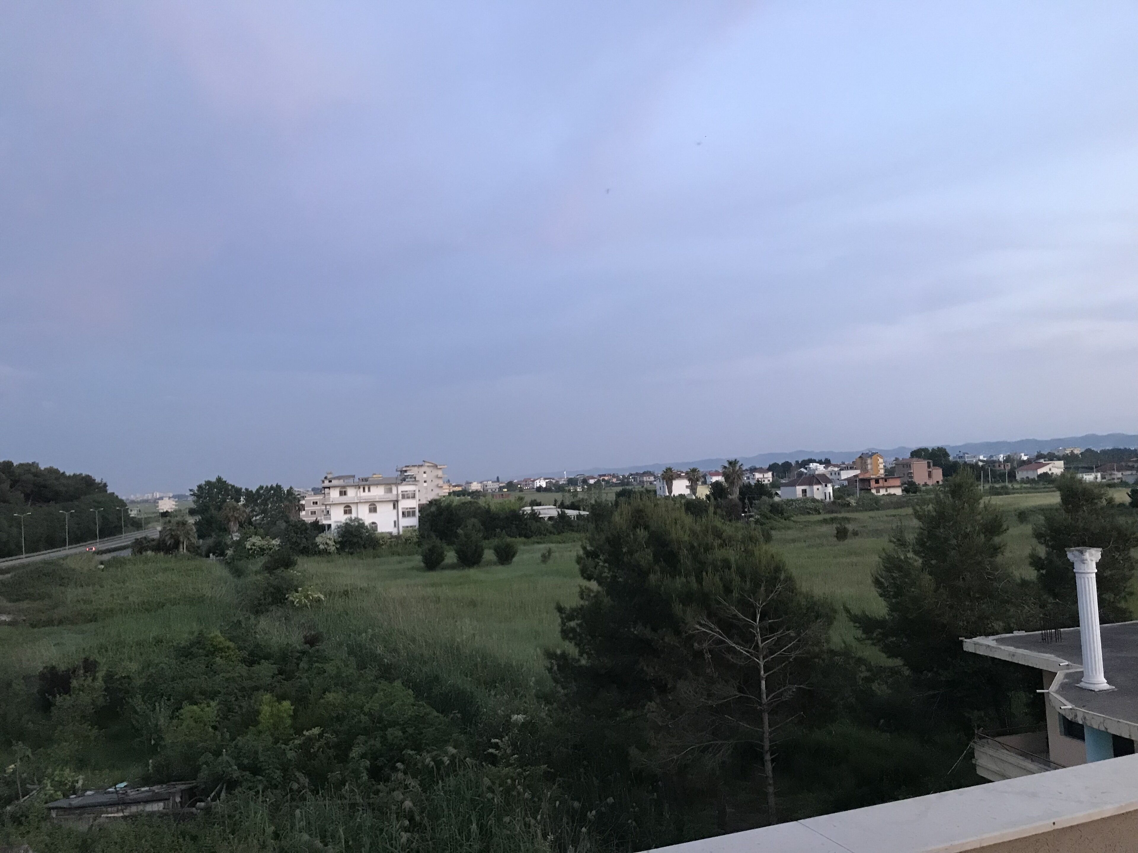 A view of a residential area with houses, greenery, and a clear sky.